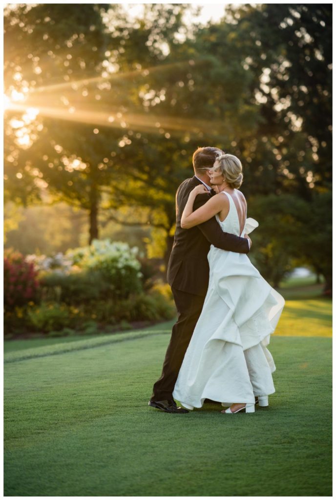 Bride and groom dancing in the sunlight on a golf course