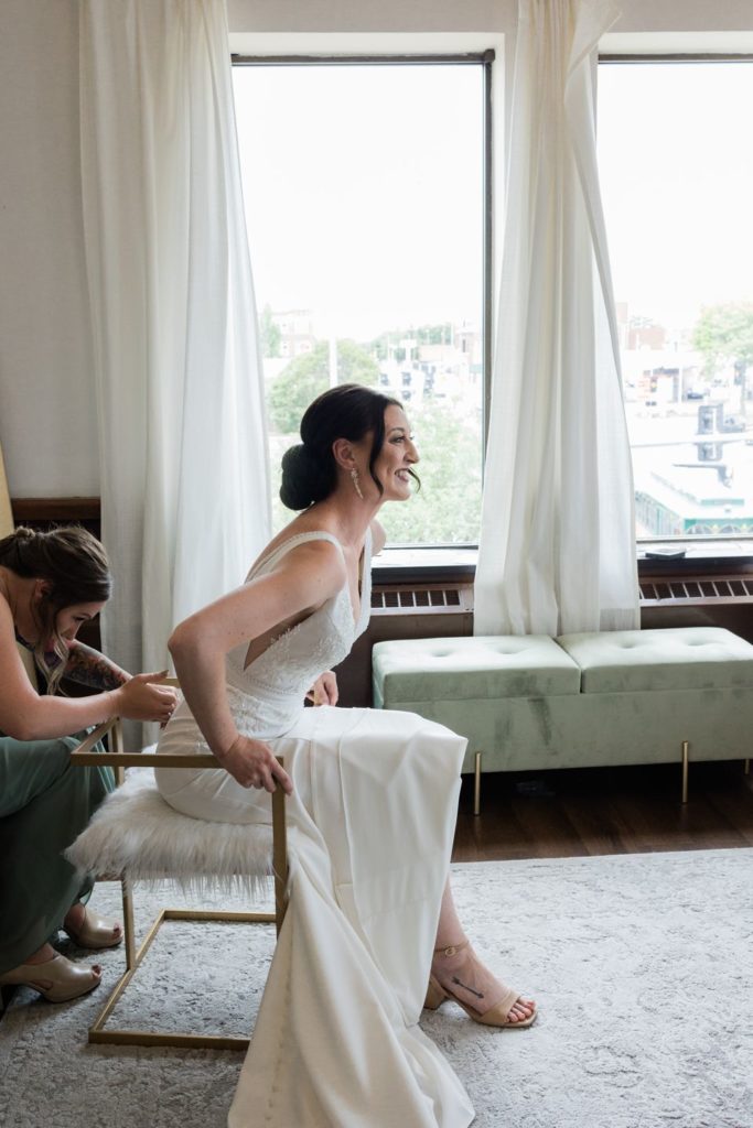 Bridesmaid zipping bride's dress