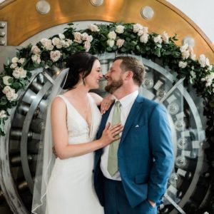 Bride and groom looking at each other in front of bank vault door